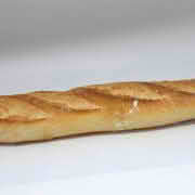 A baguette resting on a white surface, showcasing its long shape and crusty exterior