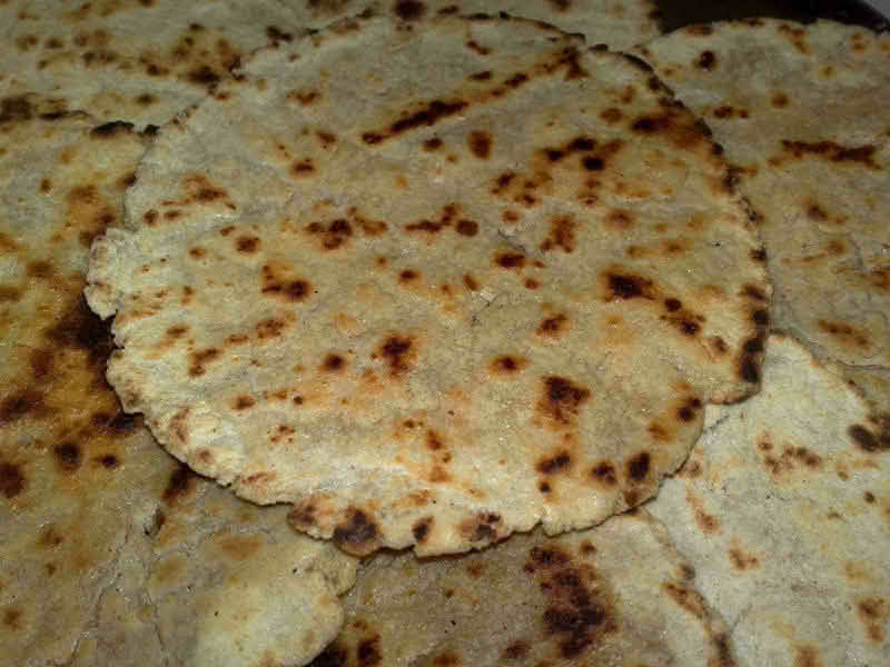 Close-up of bhakri flatbreads layered on top of one another, showcasing their texture and golden-brown color