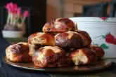 A plate stacked with freshly baked hot cross buns, made according to the recipe