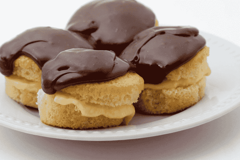 A plate featuring three Boston Cream Pies, each adorned with rich chocolate frosting