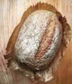 A loaf of bread resting on a rustic wooden table, showcasing its golden crust and inviting texture