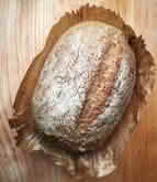 A loaf of bread resting on a rustic wooden table, showcasing its golden crust and inviting texture