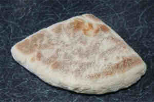 A piece of soda bread resting on a wooden table, showcasing its rustic texture and golden-brown crust