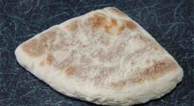 A piece of soda bread resting on a wooden table, showcasing its rustic texture and golden-brown crust