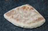 A piece of soda bread resting on a wooden table, showcasing its rustic texture and golden-brown crust